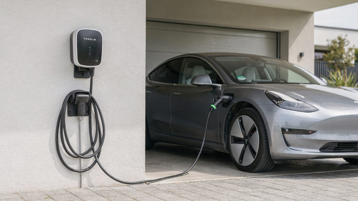 11-kW-Wallbox an der Hauswand mit angeschlossenem E-Auto in der Einfahrt