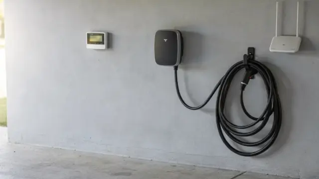 Wallbox an einer Garagenwand mit angeschlossenem Ladekabel neben Stromzähler und Router