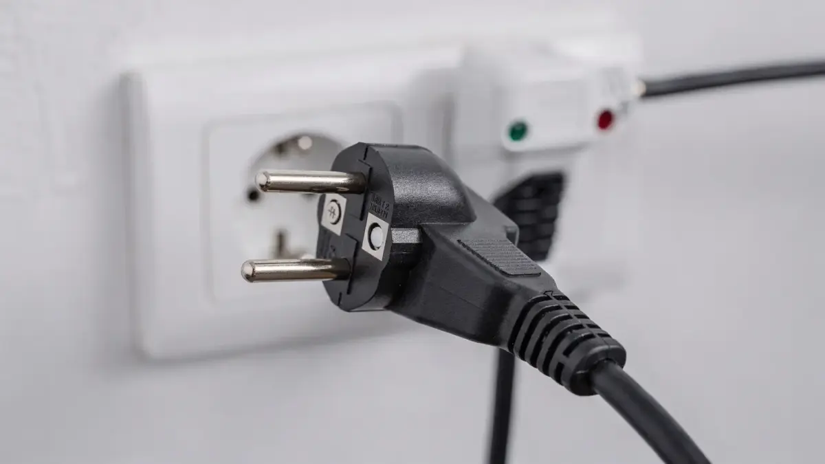 Adapter für ein Ladekabel mit Schutzkontakt neben einer Wallbox-Steckdose und sichtbaren Kontaktpins