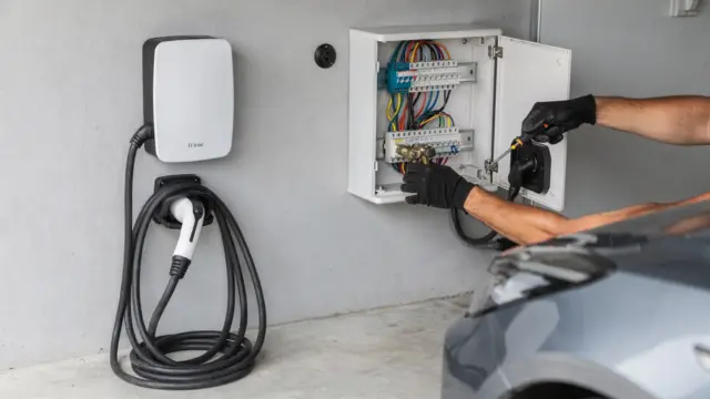 Elektroinstallateur prüft eine 11-kW-Wallbox beim Anschluss in der Garage