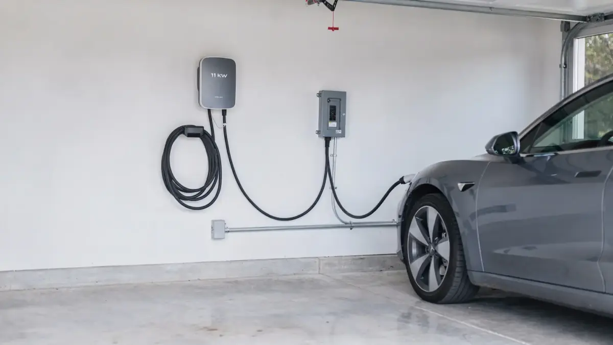 11-kW-Wallbox in der Garage an der Wand neben Elektroauto und Sicherungskasten