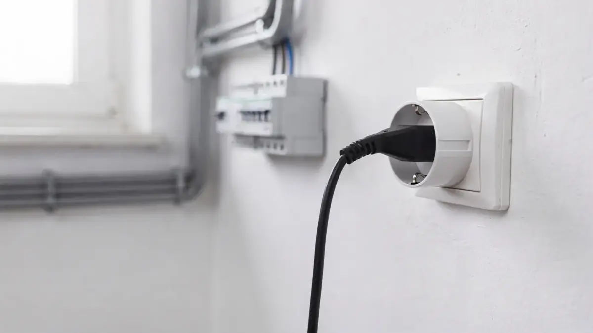 Schuko-Steckdose mit angeschlossenem Ladekabel in einer Garage beim Laden eines Elektroautos.